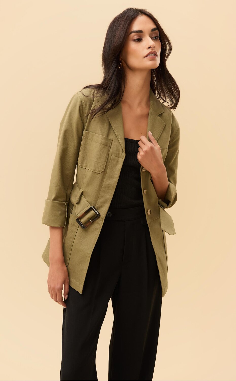 Woman wearing an army green jacket, black tank top and black pants, woman wearing a dark wash denim dress
