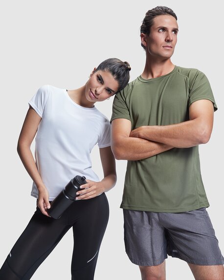 En kvinne i hvit Roly-treningstopp lener seg mot en mann i olivengrønn Roly-treningstopp, begge i sporty klær og med en vannflaske.