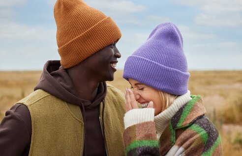 Mann og kvinne med fargerike luer fra Beechfield, smilende ute i naturen