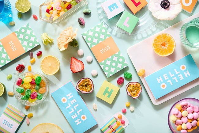 Fargerike drops og karameller med logotrykk i esker og poser, omringet av sitrusfrukter og sukkertøy. Perfekt profileringsgodteri for messer, events og kampanjer.