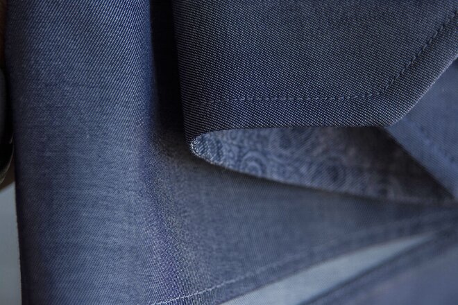 Nærbilde av en mørk blå skjorte med synlige sømmer og tekstur i stoffet. Kvalitetsskjorte for bedrifter som ønsker slitesterke og stilrene profileringsklær.