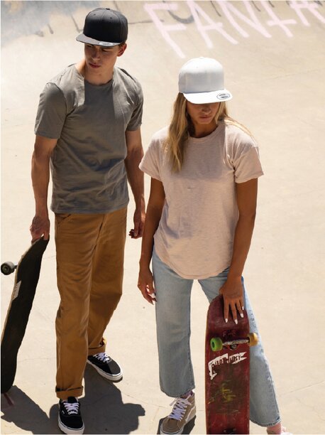 En mann og en kvinne i Flexfit-caps, stående med skateboards i en skatepark.