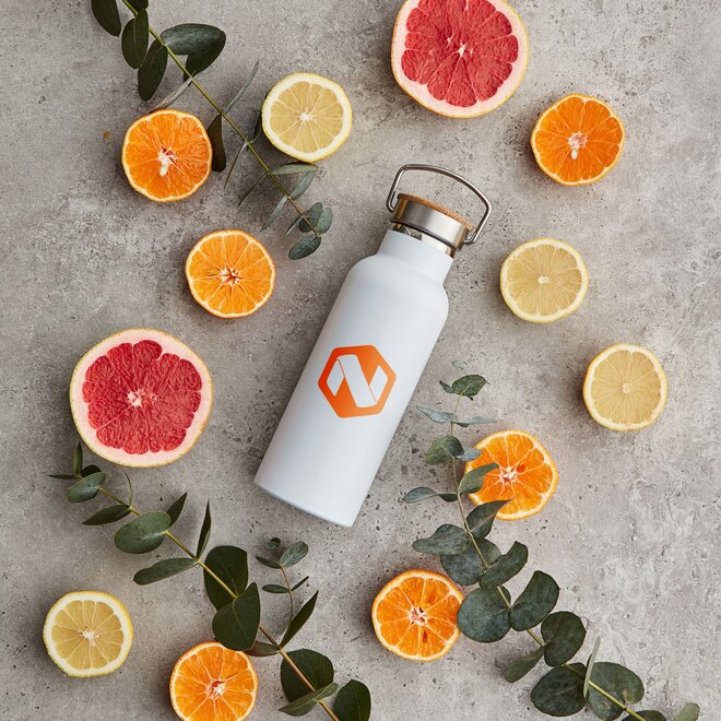 Elegant hvit termoflaske med trykket firmalogo, omringet av grapefrukt og sitrusfrukter. Miljøvennlig profileringsflaske for giveaways og bedriftsbranding.