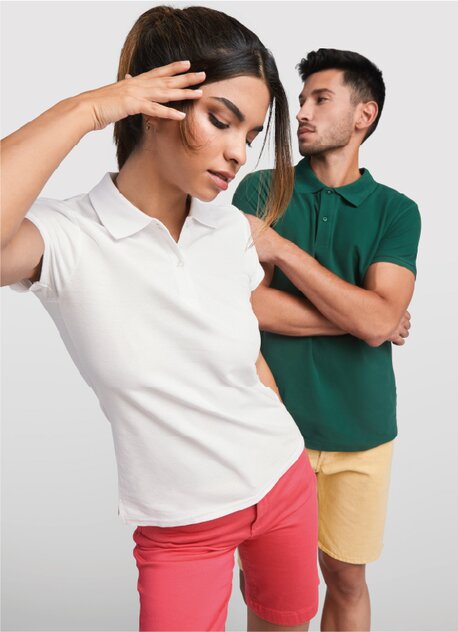Kvinne i hvit Roly-pique og røde shorts, og mann i grønn Roly-pique og gule shorts.