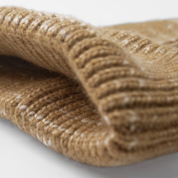 Nærbilde av en beige strikkelue med ribbestrikket kant, som fremhever den myke teksturen og høye kvaliteten på materialet. Perfekt for både stil og varme på kalde dager.