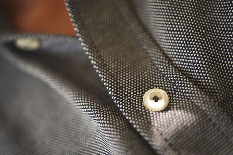 Nærbilde av en gråmønstret skjorte med en perlemorsknapp.