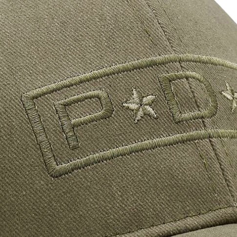 Nærbilde av brodering på caps – Olivengrønn caps med hevet brodert logo i matchende fargetone. Broderiet gir et strukturert og eksklusivt utseende, perfekt for profileringscaps.