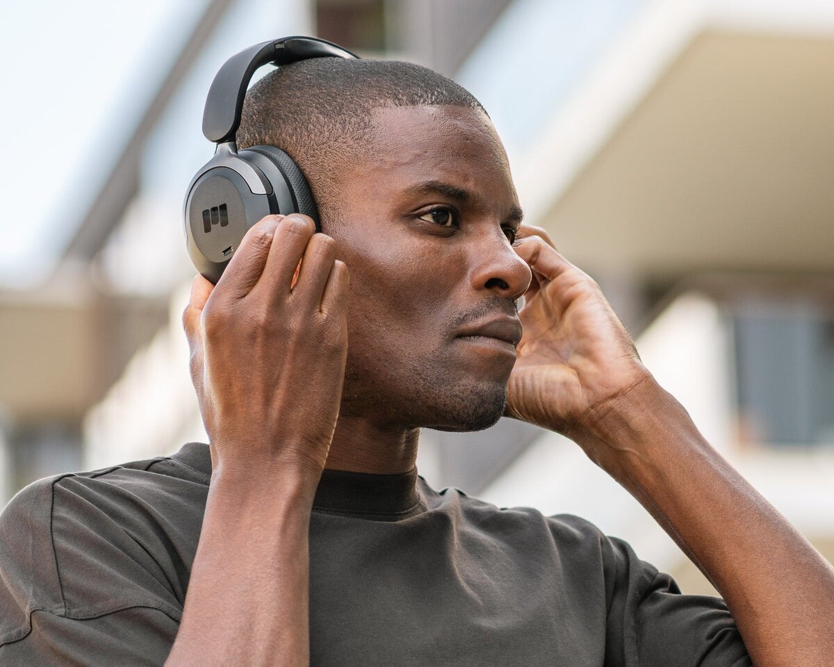 Mann justerer et par Miiego Moove 55 Silence over-ear-hodetelefoner mens han står ute.