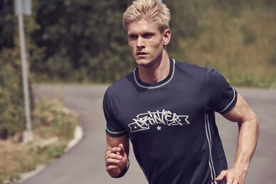 Mann i mørkeblå treningsskjorte fra Printer, løpende på en landevei.