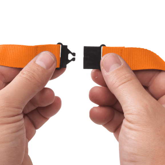 Hender som åpner en svart hurtigspenne på et oransje nøkkelbånd. Praktisk og brukervennlig løsning for sikkerhet og fleksibilitet.