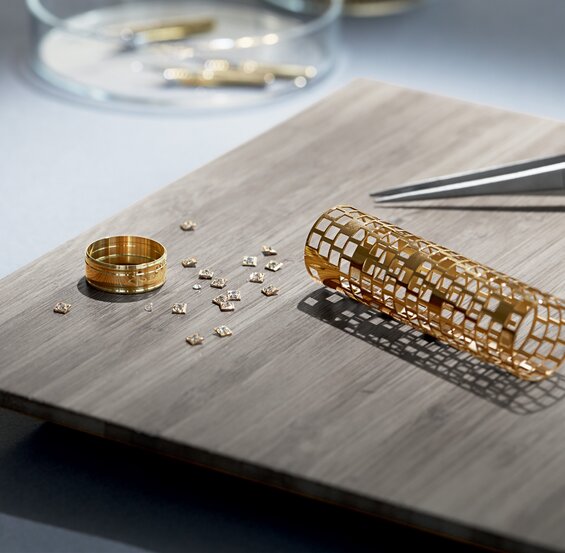 Produksjon av en gullring med diamanter til bruk på eksklusiv Parker-penn, med små diamantbiter spredt utover en treplate.