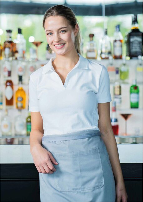 Kvinnelig servitør i hvit Tracker poloskjorte foran bardisk 