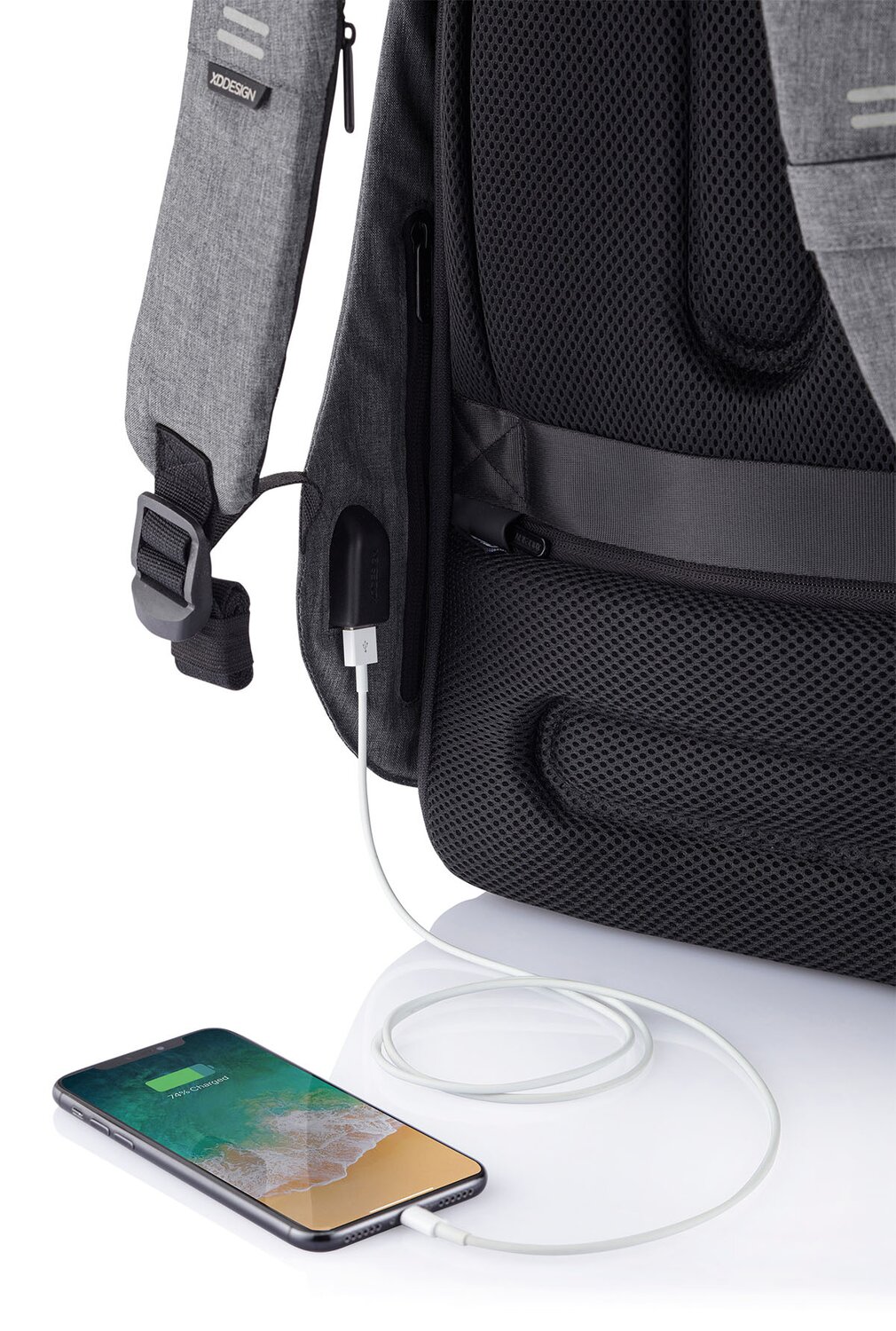 Moderne ryggsekk med innebygd USB-ladeport, koblet til en smarttelefon via hvit ladekabel. Sekken har en stilren design i grått og svart med justerbare stropper, perfekt for arbeid, studier eller reise.