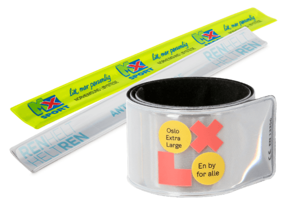 Tre ulike slapwrap-reflekser designet for synlighet i mørket. Den øverste refleksen er neongul med logo og slagord i blått, mens den midterste er sølvgarget med lys tekst trykt under refleksmaterialet. Den fremste refleksen er sølvfarget med trykte former og tekst, og er rullet sammen for å vise fleksibiliteten. Perfekt som profilartikkel for sikkerhet og merkevareeksponering.