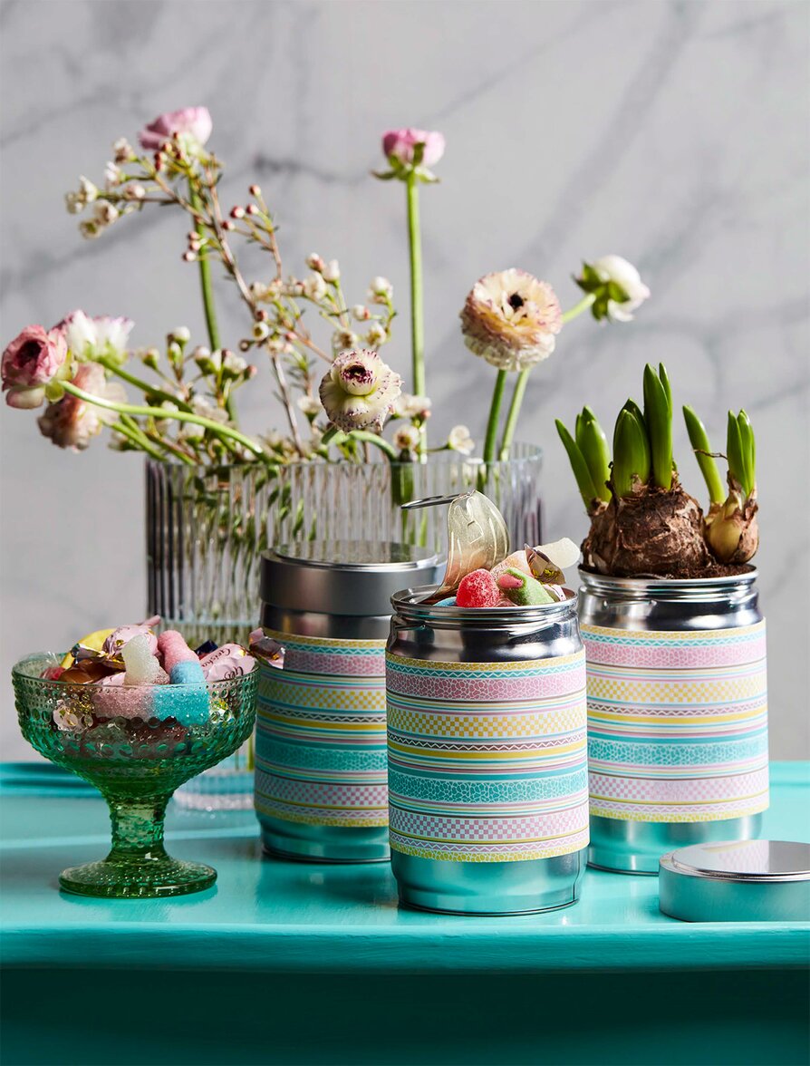 Metallbokser med fargerik etikett og påskegodteri – en kreativ påskegaveidé.