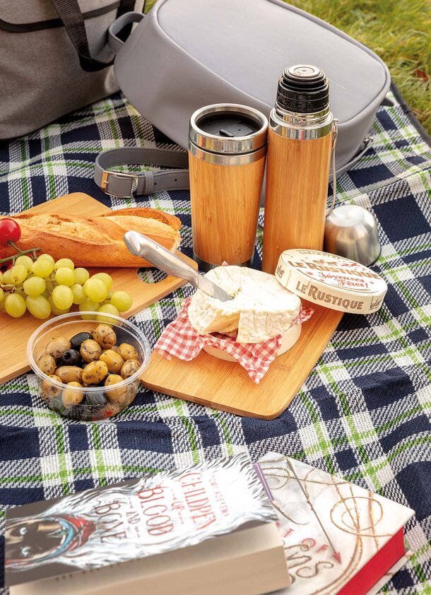 Piknikoppsett på rutete teppe med bambus-termoser, ost, brød og druer fra XD Collection.