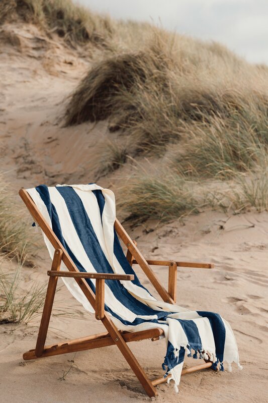 Strandstol med håndkle i sanddyner – sommerprodukter og firmagaver til strand og ferie