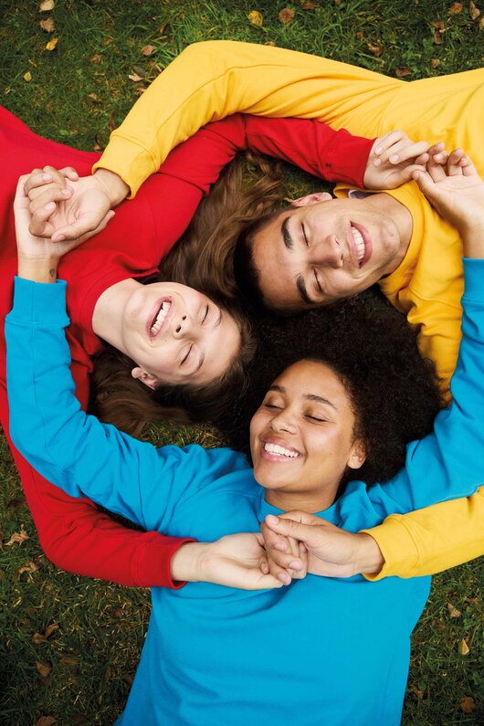 Tre smilende modeller i fargerike Neutral T-skjorter i økologisk bomull – bærekraftige profilklær med fokus på komfort, fellesskap og ansvarlig produksjon