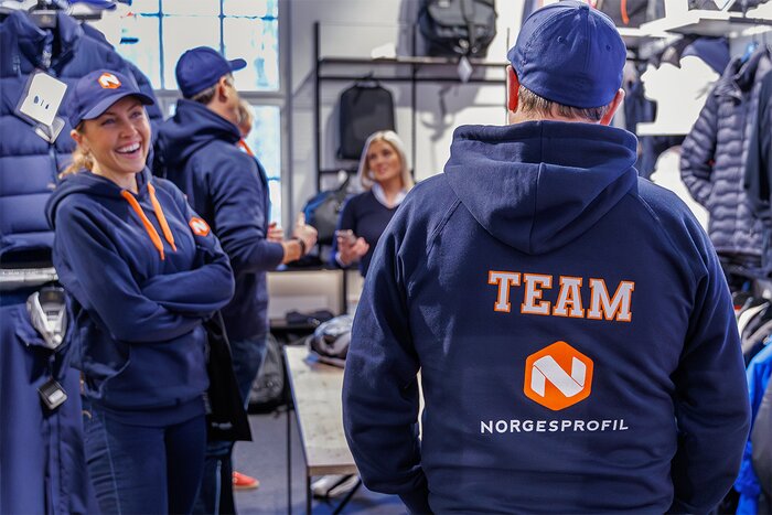 Marineblå hettegenser med brodert og trykket firmalogo og teksten "TEAM". Perfekt for ansatte, eventer og teamwear for økt profilering og profesjonelt utseende