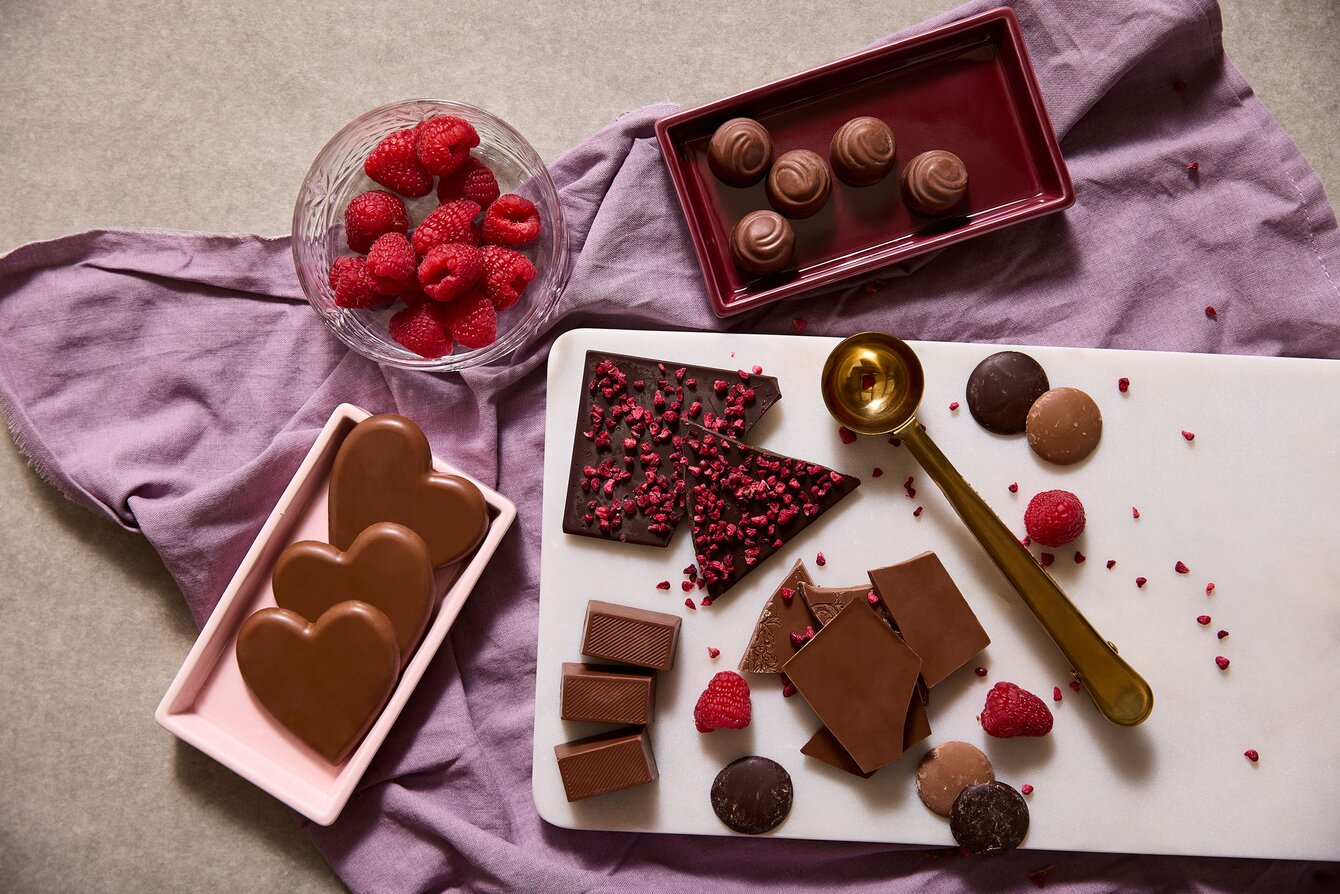 Høykvalitets sjokolade i hjerteform og mørk sjokolade med frysetørkede bringebær, servert med friske bringebær og elegante detaljer. Perfekt som profileringssjokolade eller eksklusive firmagaver.