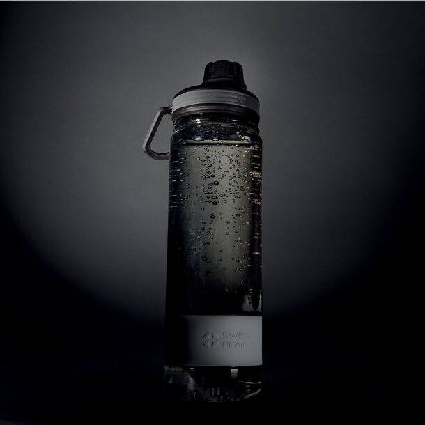 Gjennomsiktig Swiss Peak-drikkeflaske fylt med vann, fotografert i et mørkt studio.