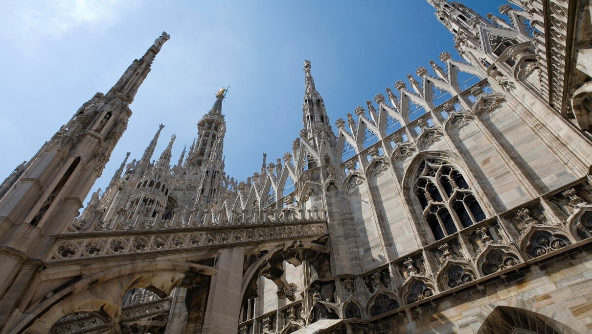 A Gothic cathedral with intricate spires and richly decorated stone details against a clear blue sky.