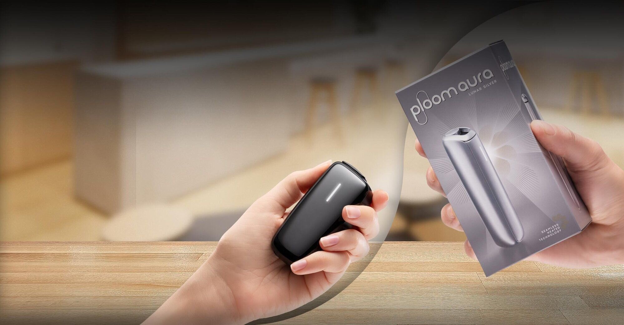 A person holds a Ploom AURA Rose Gold device with a tidy wardrobe and covers in view.