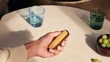 Woman is drinking Ploom coffee and holding the Ploom X Advanced Red.