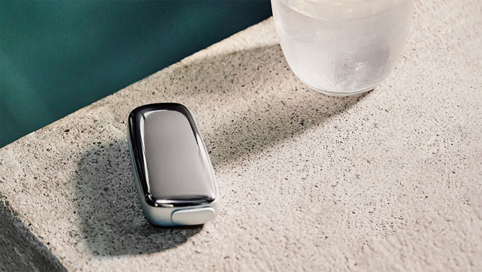 Ploom device on the edge of a pool next to a glass of cold drink.   