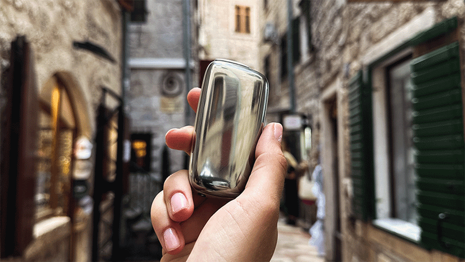 A person holding a Ploom device on a narrow stone street in Montenegro.