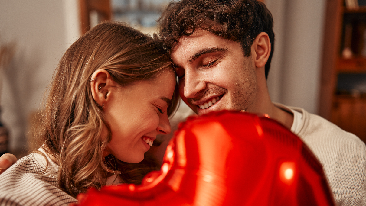 Zaljubljeni par se grli i drži balon u obliku srca