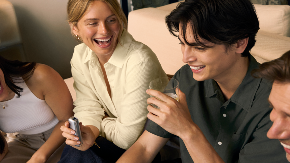 Friends laughing and socializing while holding a Ploom device.