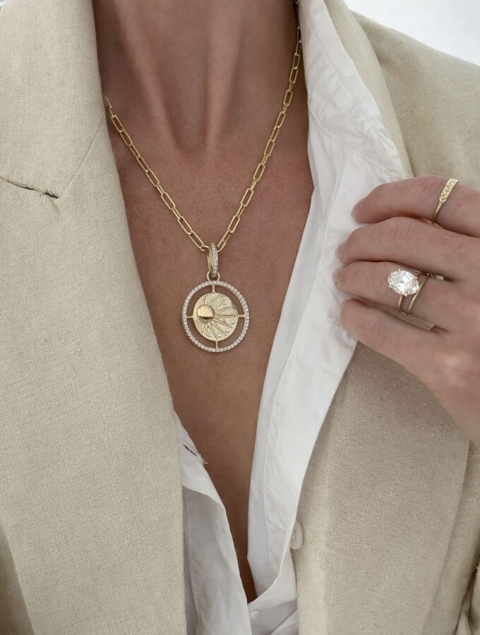 A person wearing a yellow gold medallion necklace