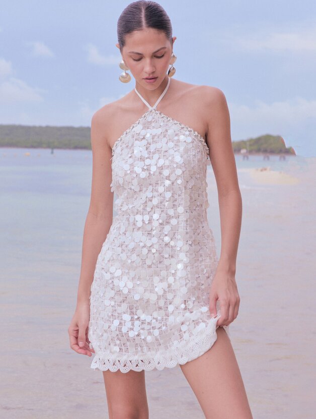 A woman in a white sequined halter mini dress