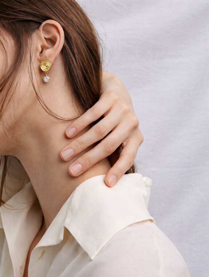 A woman wearing a pair of yellow gold and diamond drop earrings