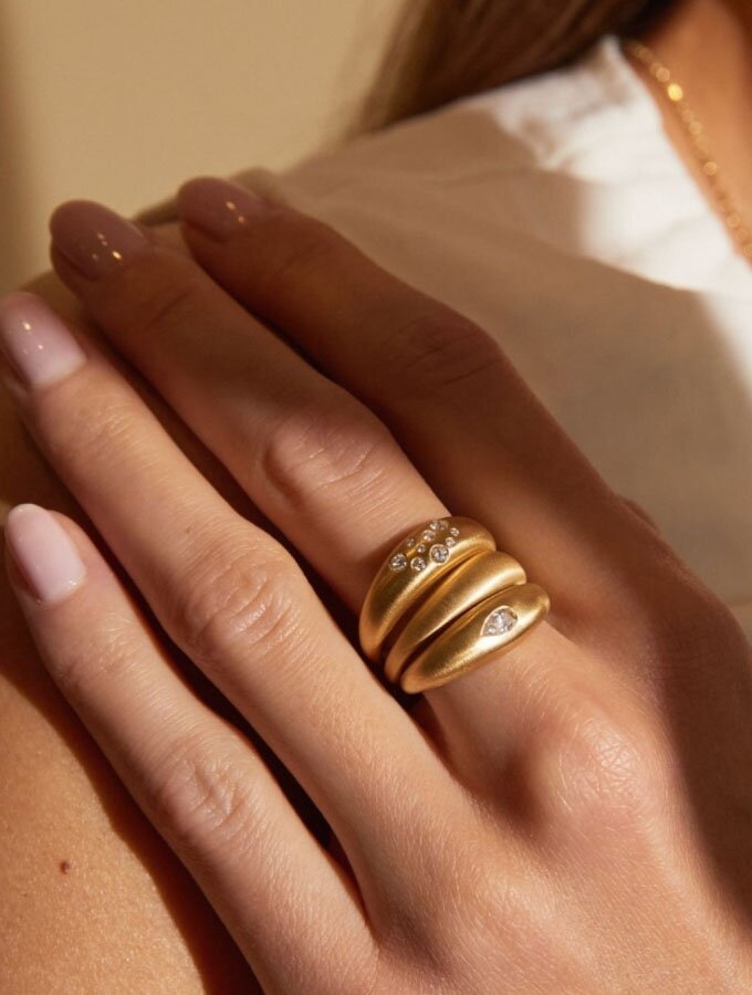 A person wearing a stack of yellow gold rings with diamond embellishments