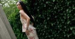 A woman wearing a dark grey herringbone wool blazer with a set of yellow gold, diamond-embellished necklace, rings, ear cuff and bangle