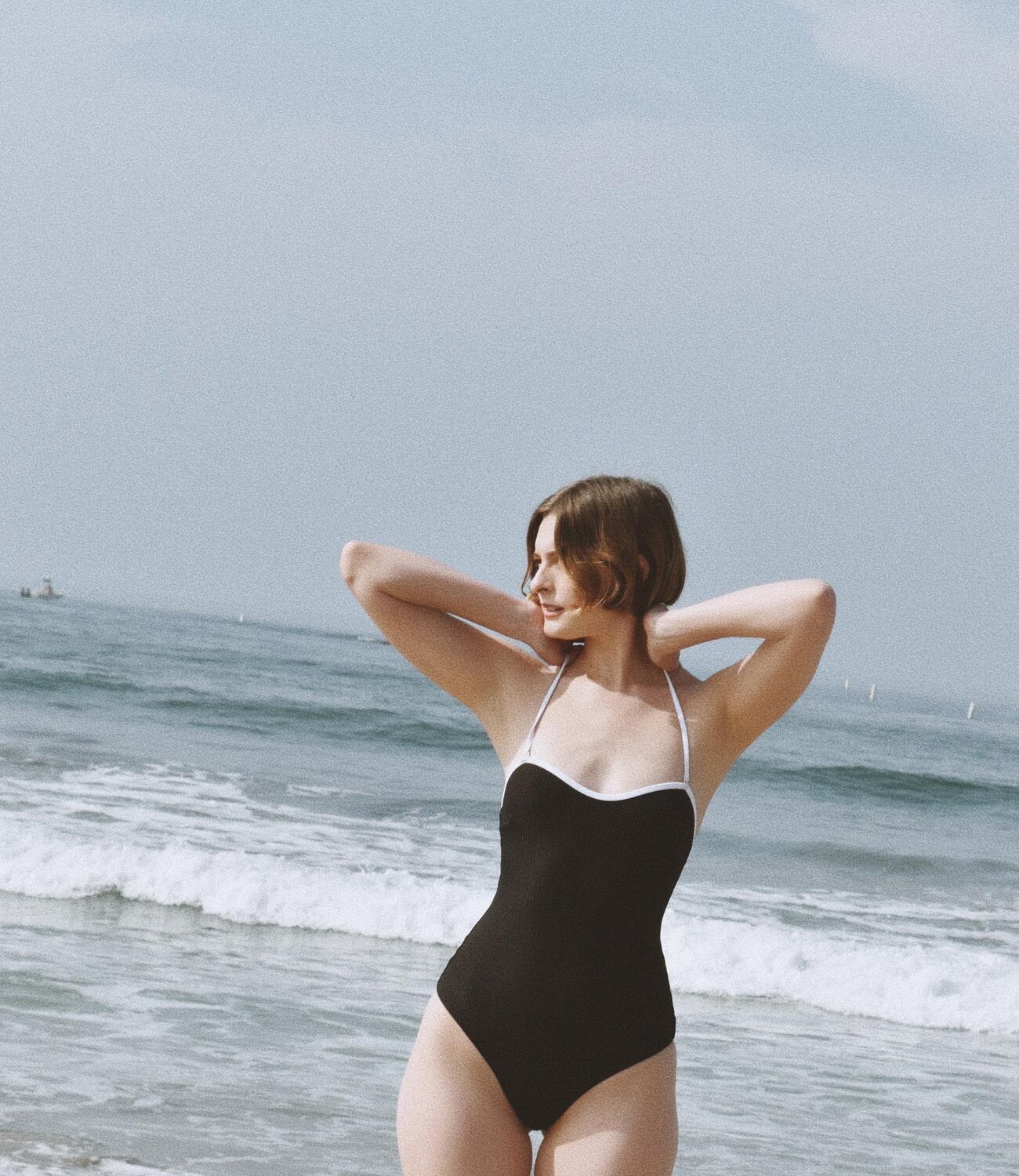 A woman wearing a dark grey herringbone wool blazer with a set of yellow gold, diamond-embellished necklace, rings, ear cuff and bangle