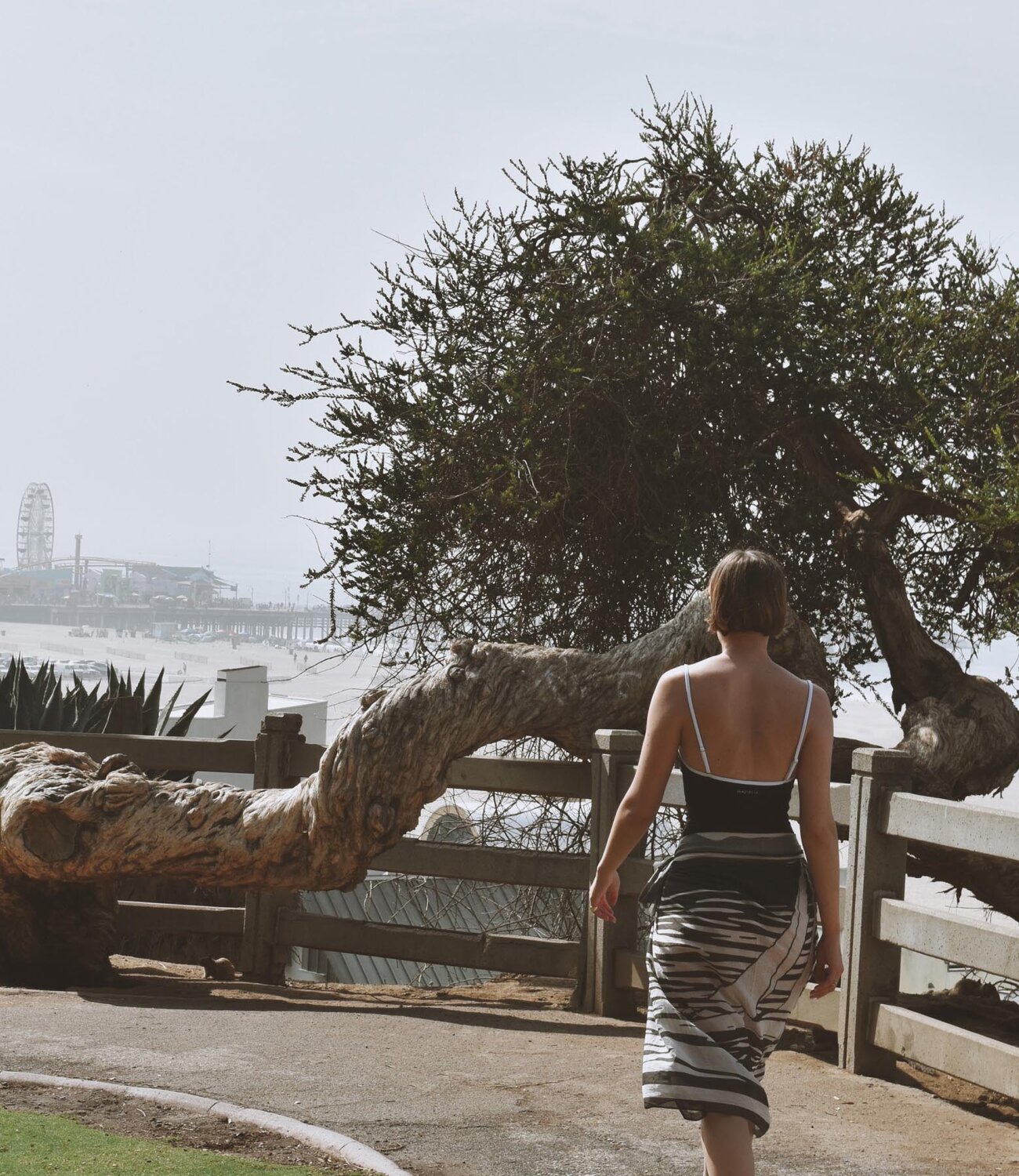A woman wearing a dark grey herringbone wool blazer with a set of yellow gold, diamond-embellished necklace, rings, ear cuff and bangle