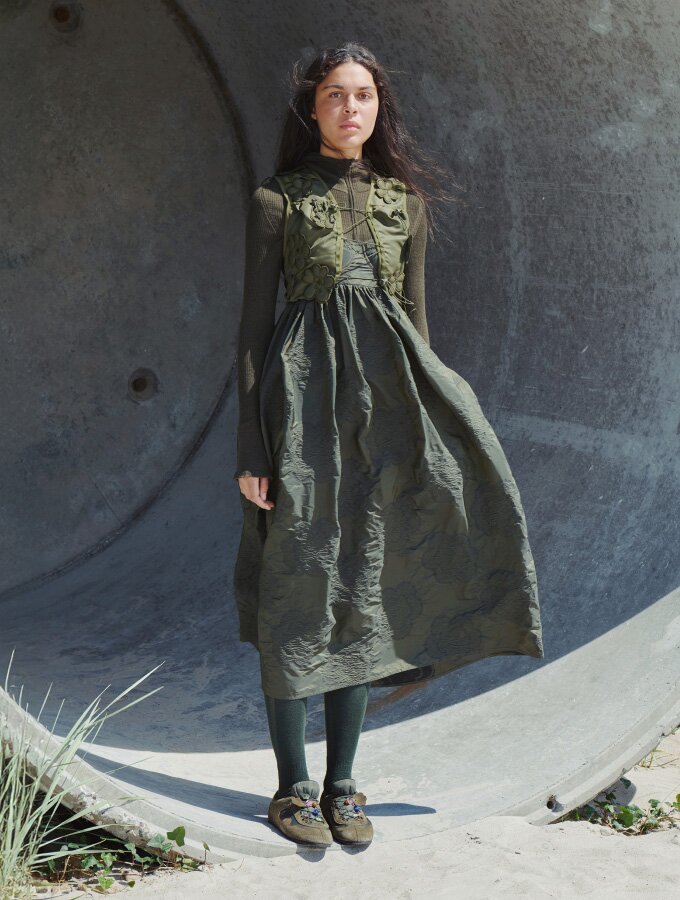 A female model wearing a monochromatic army green long-sleeved knit top, dress, tights and ballet flats