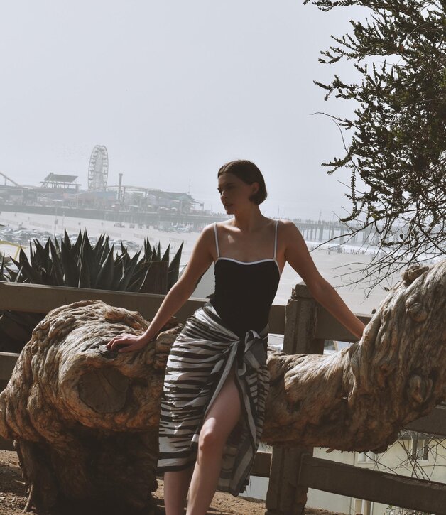 A woman wearing a dark grey herringbone wool blazer with a set of yellow gold, diamond-embellished necklace, rings, ear cuff and bangle
