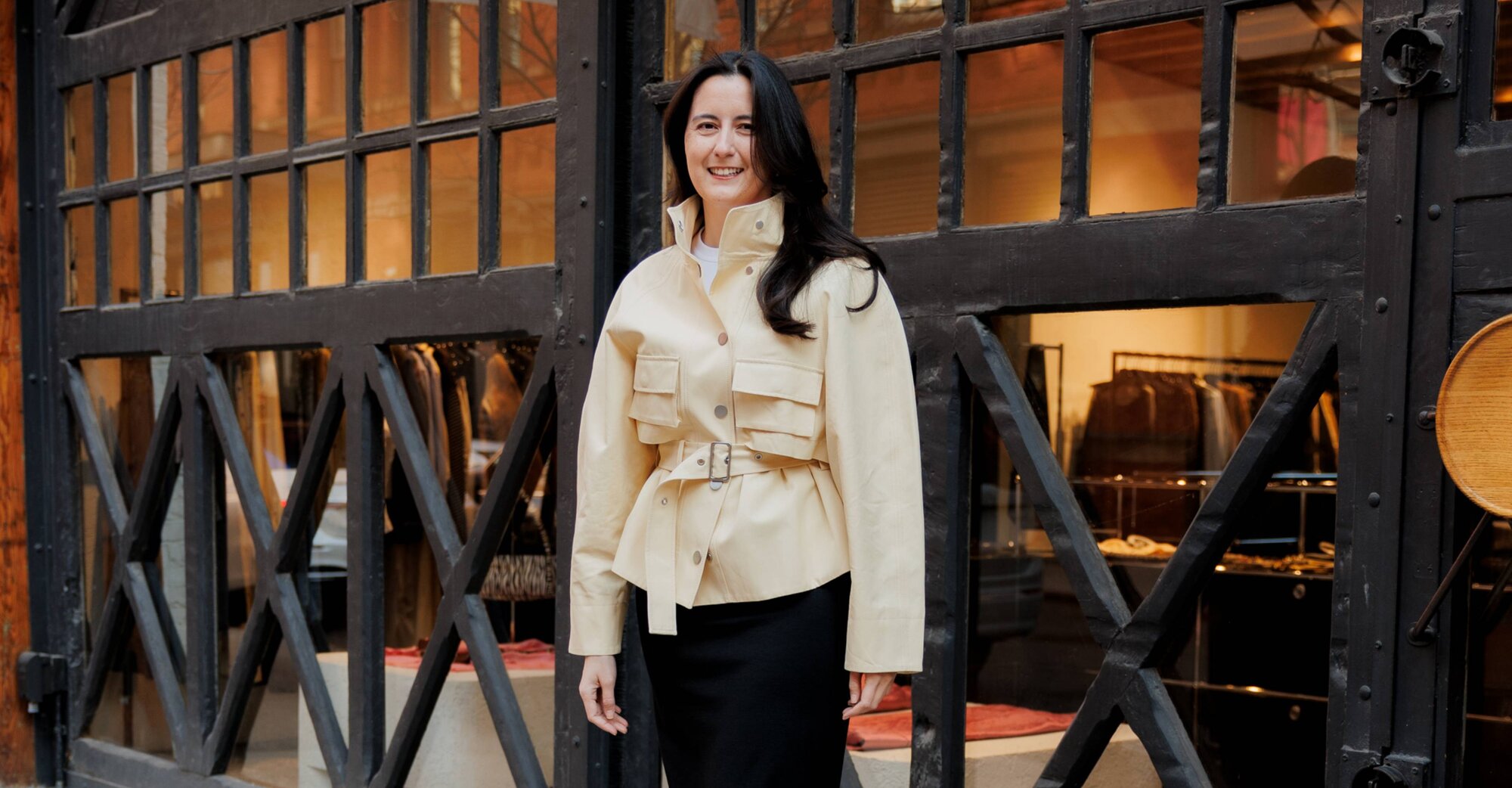 A woman wearing a dark grey herringbone wool blazer with a set of yellow gold, diamond-embellished necklace, rings, ear cuff and bangle