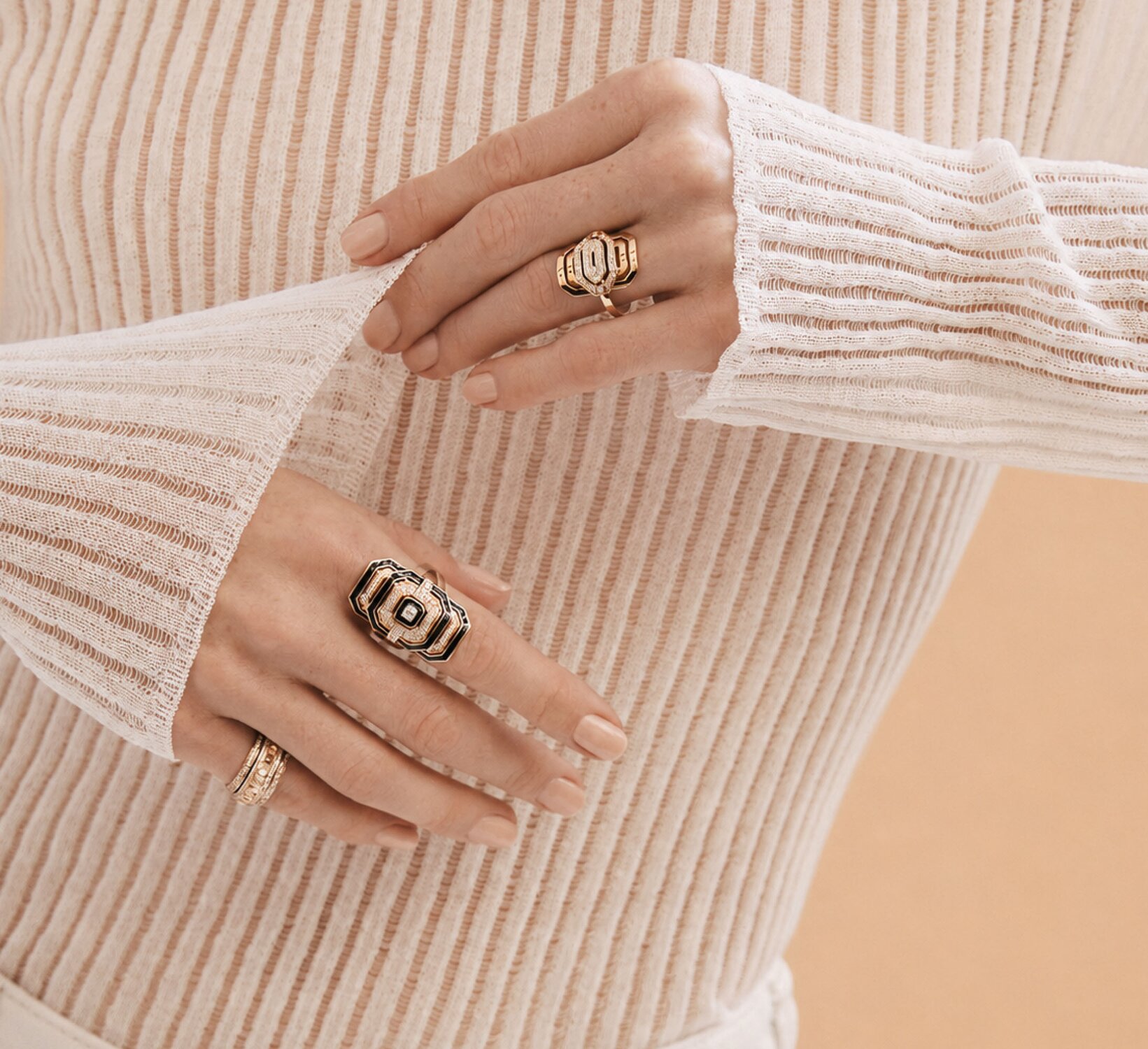 A woman wearing a dark grey herringbone wool blazer with a set of yellow gold, diamond-embellished necklace, rings, ear cuff and bangle