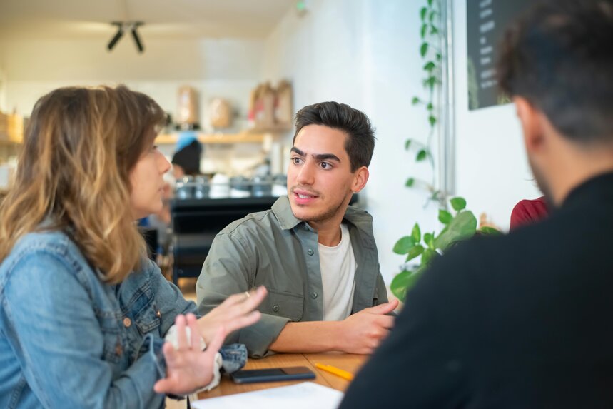 Une discussion calme entre trois amis dans un salon.