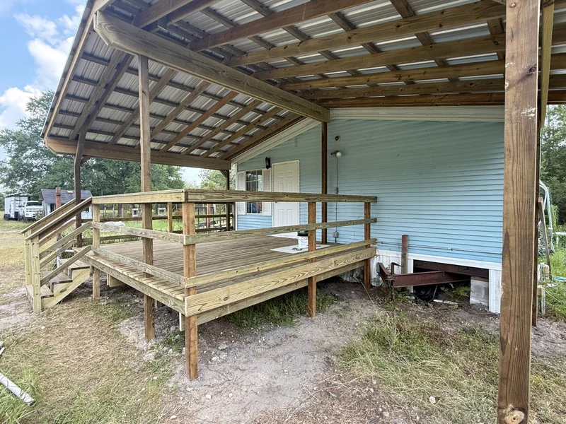 Covered entry ramp with wood rails beside a home