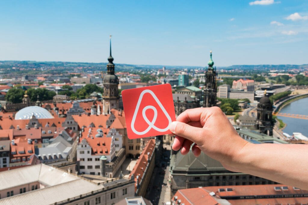 A hand holding an Airbnb logo 