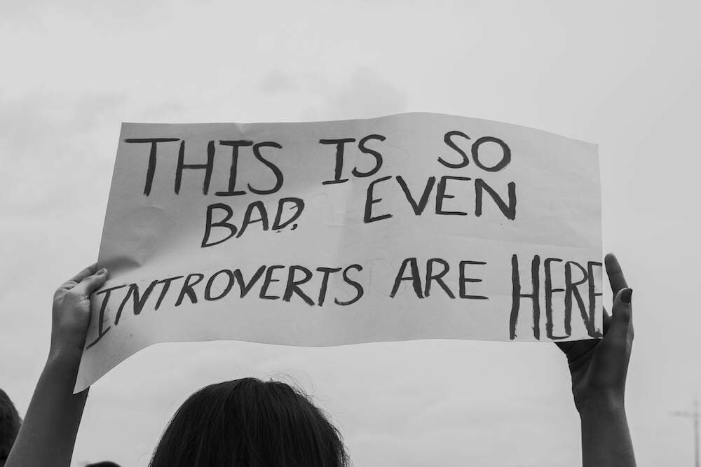 person holding up a sign saying this is so bad even introverts are here