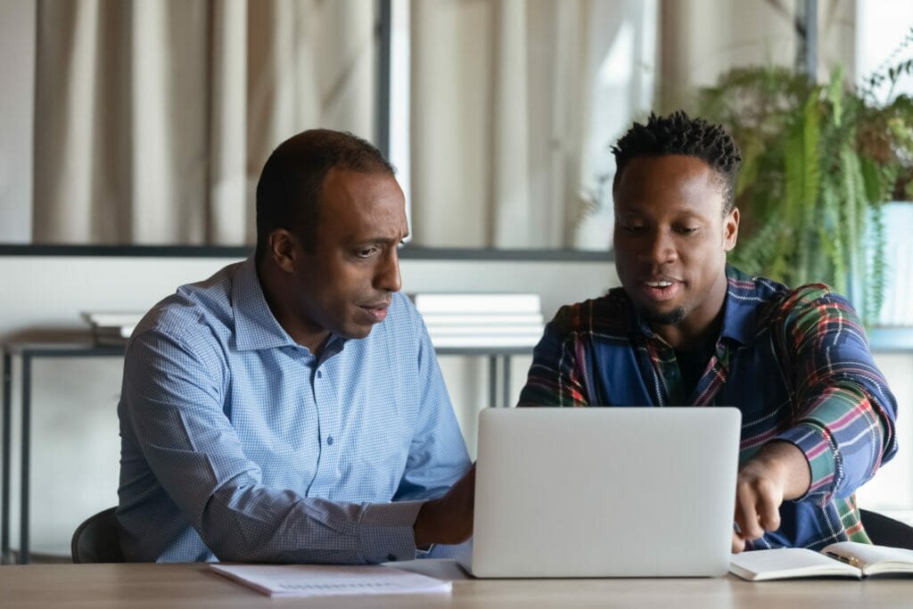 two men looking at a laptop together shutterstock image