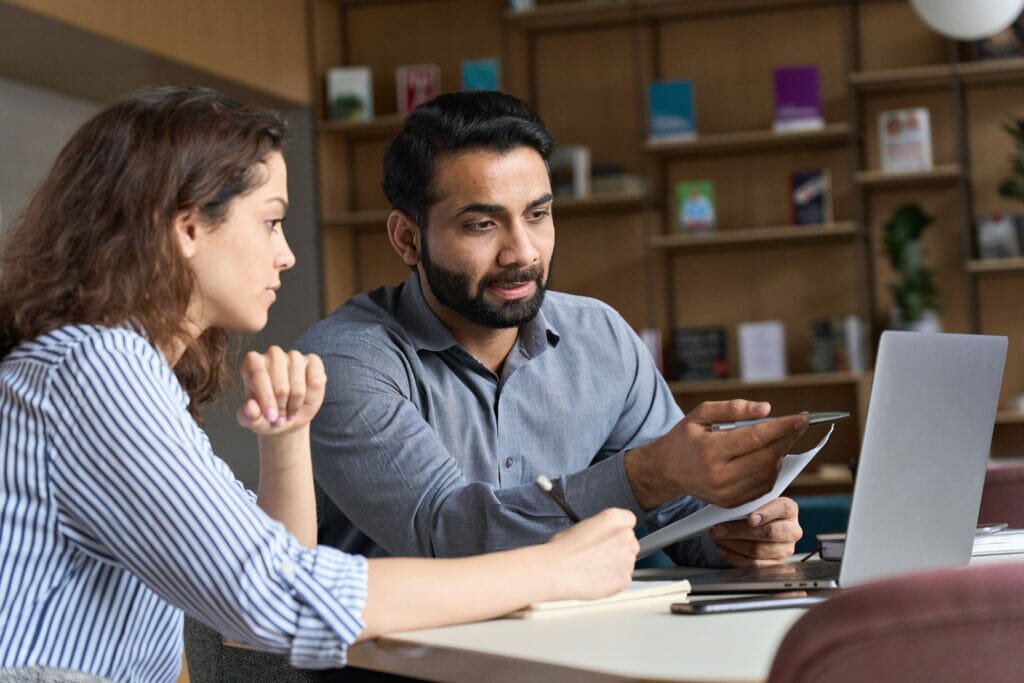 Man and a woman discussing something in front of a laptop shutterstock image
