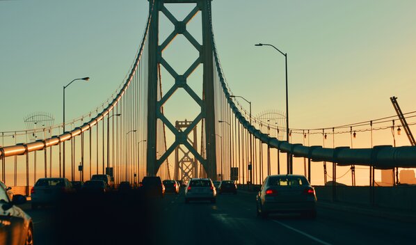 Vehicles on oakland bay bridge against sky at sunset